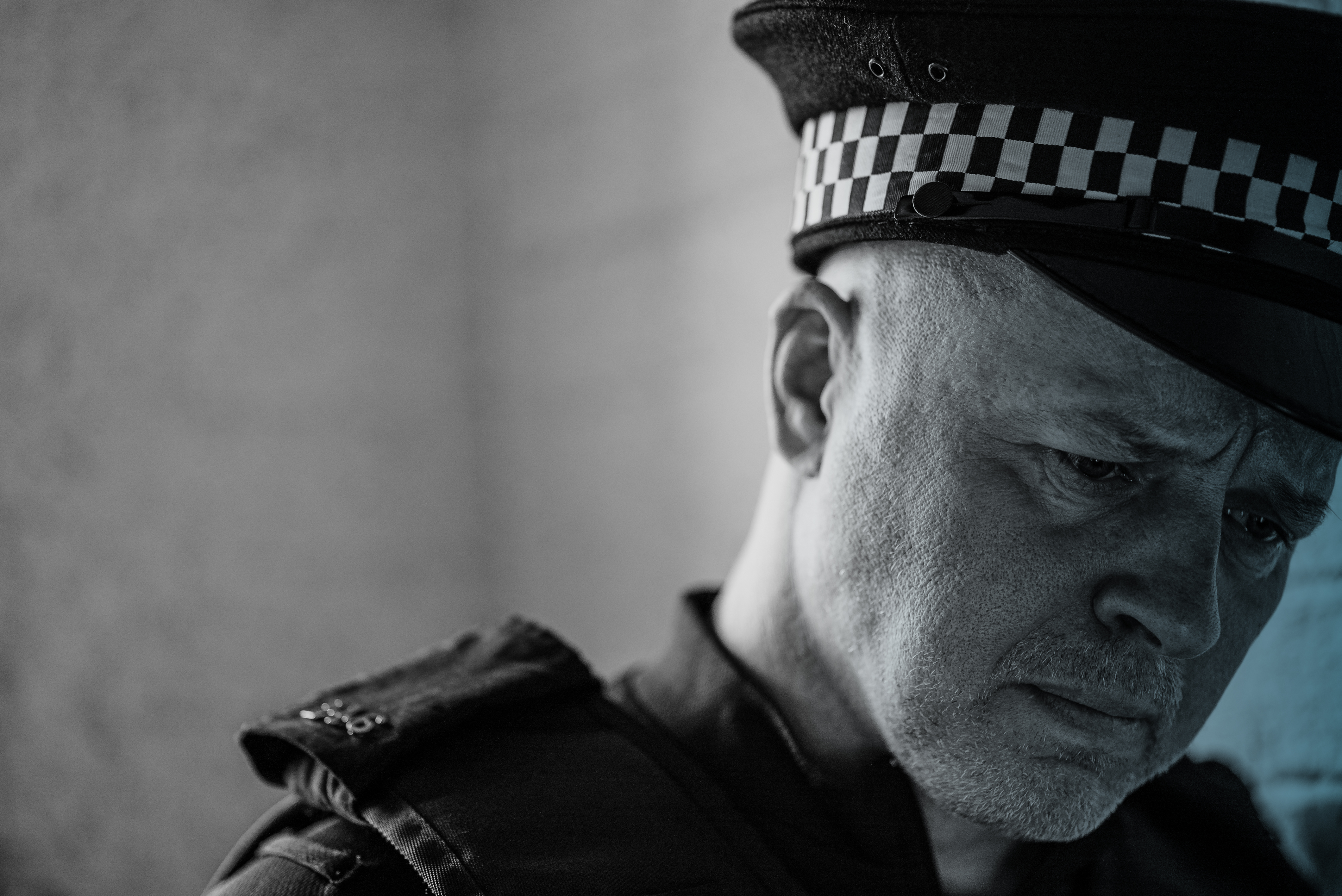 An image of a white male police officer in uniform, with a very serious or sad expression